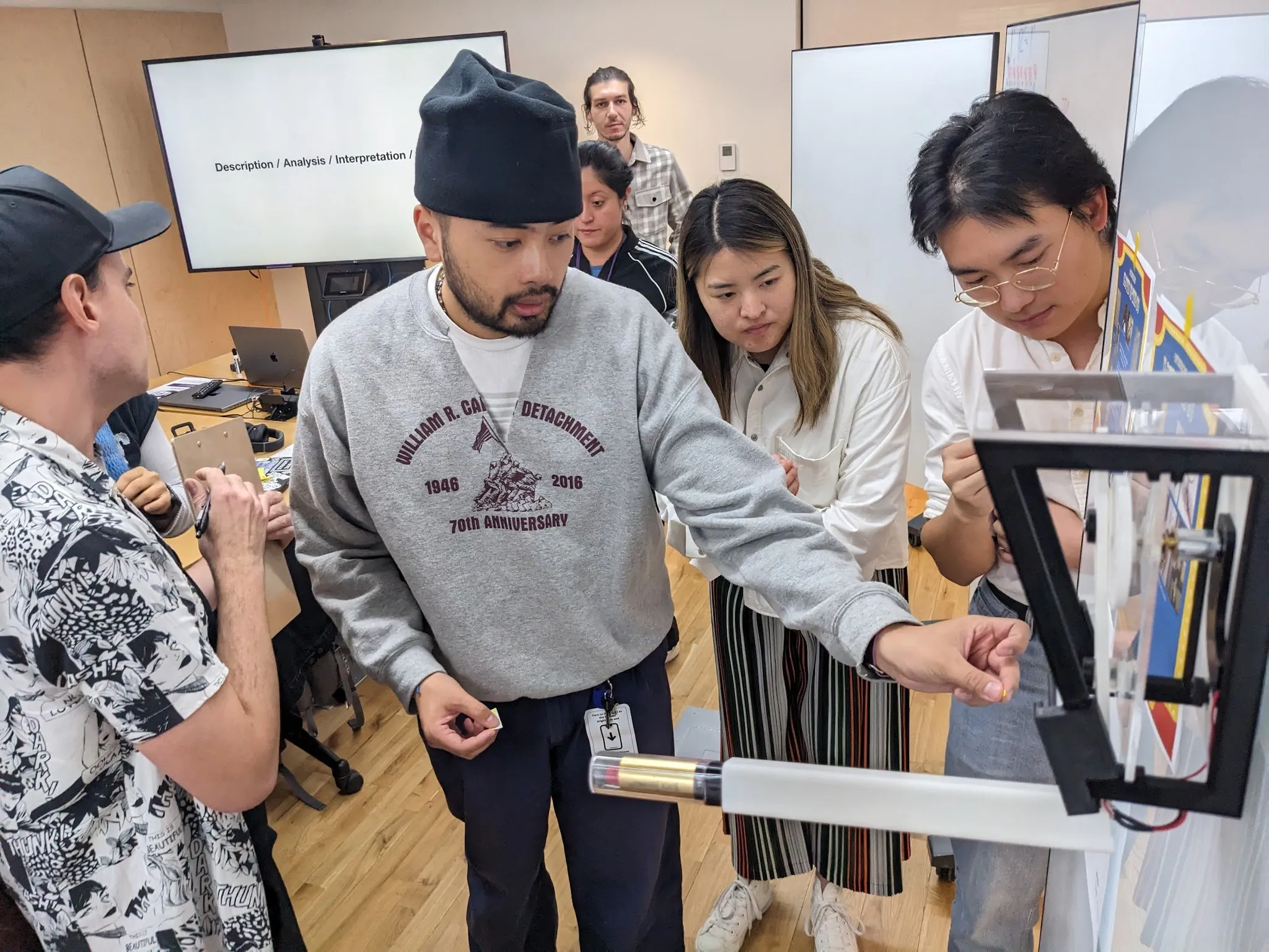 Classmates gathered around the finished device in the studio, taking turns trying it out.