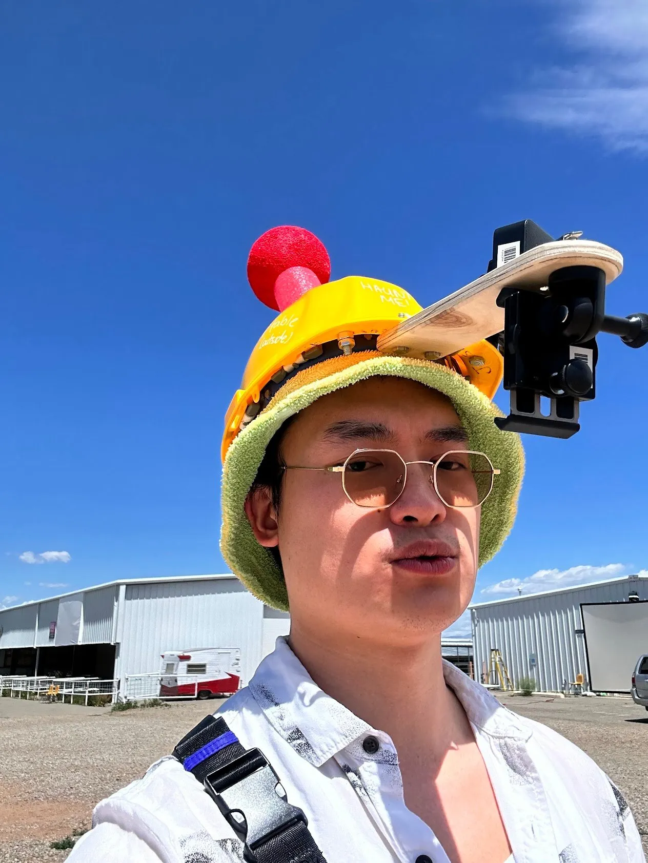 A classmate outdoors wearing a colorful knitted hat rigged with a phone mount and armature.