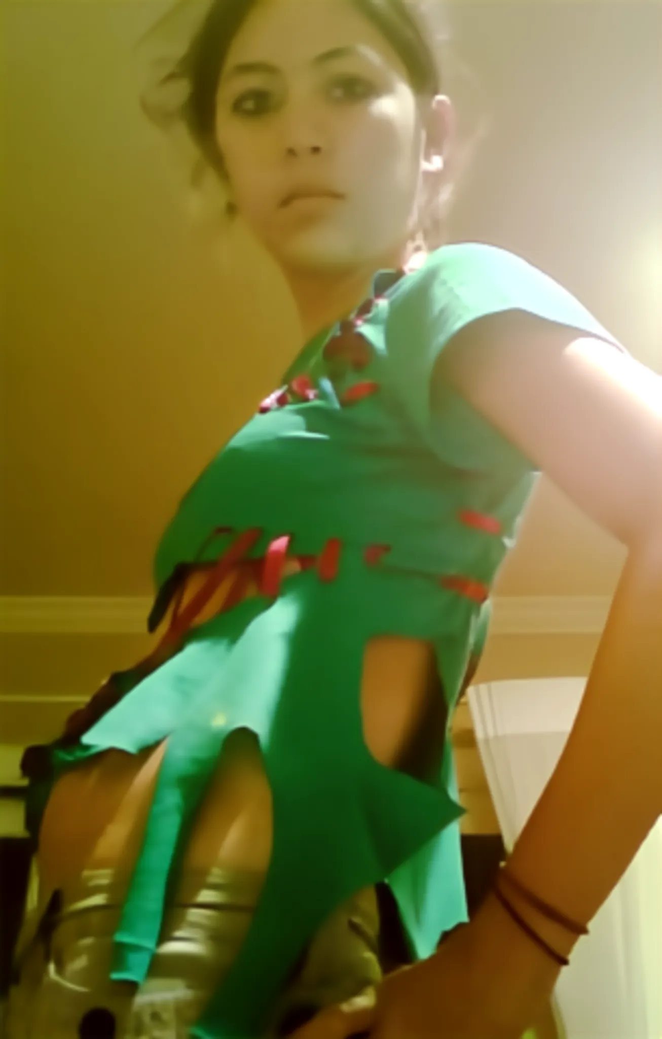 Photograph of a girl wearing a torn up green shirt, side