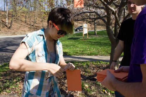 Photograph of a girl tying string onto orange rectangles