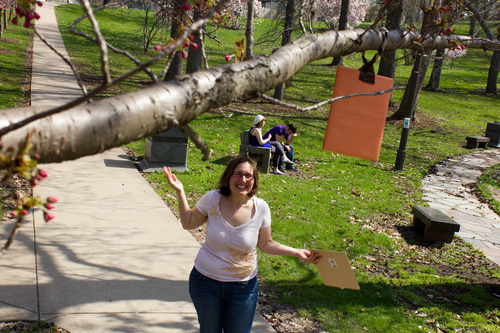 Photograph taken from a tree looking down at a woman laughing while holding an orange rectangle