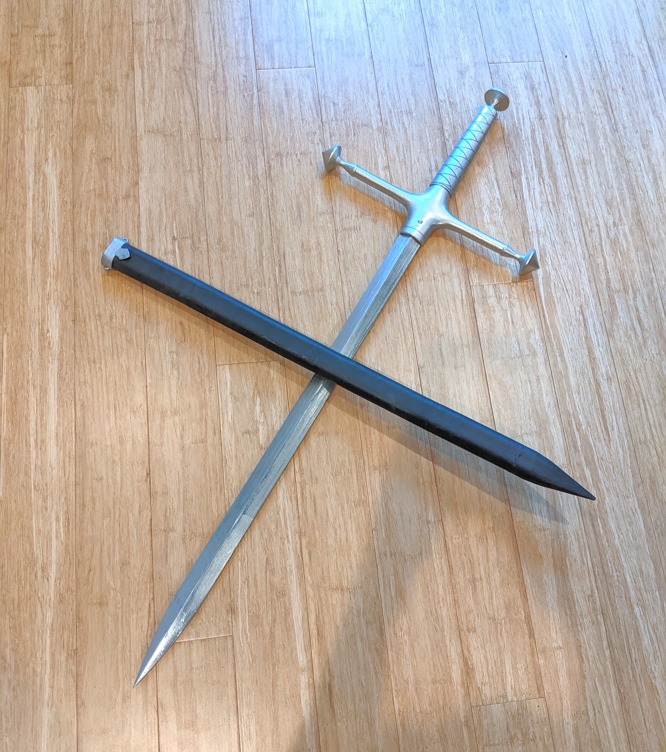 Photograph of a painted silver sword and a black sheath crossed on the floor