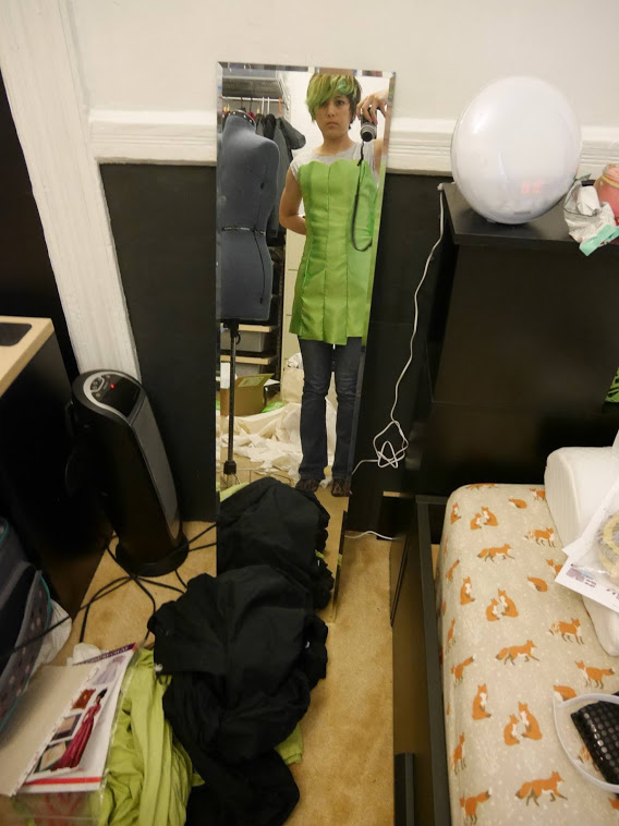 Photograph of a girl looking in a mirror figuring out the fit of green fabric