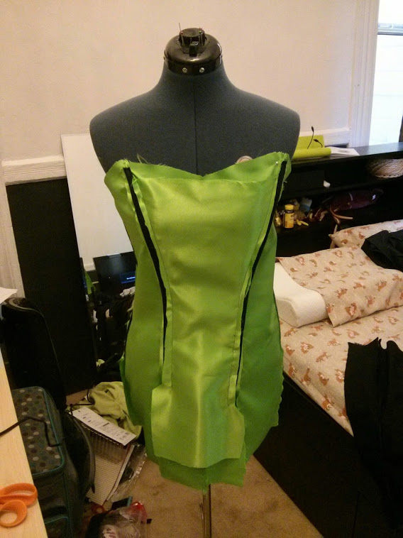 Photograph of green fabric with black boning wrapped around a mannequin