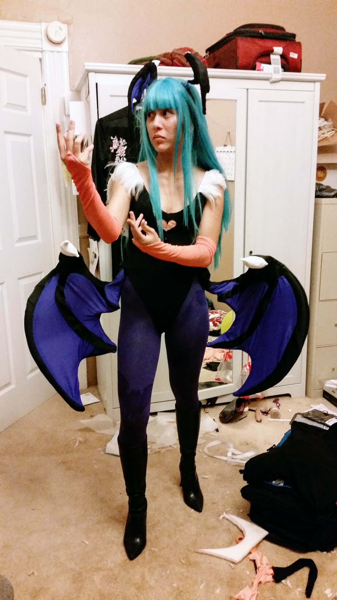 Photograph of a girl wearing a teal wig and a giant set of wings around her waist