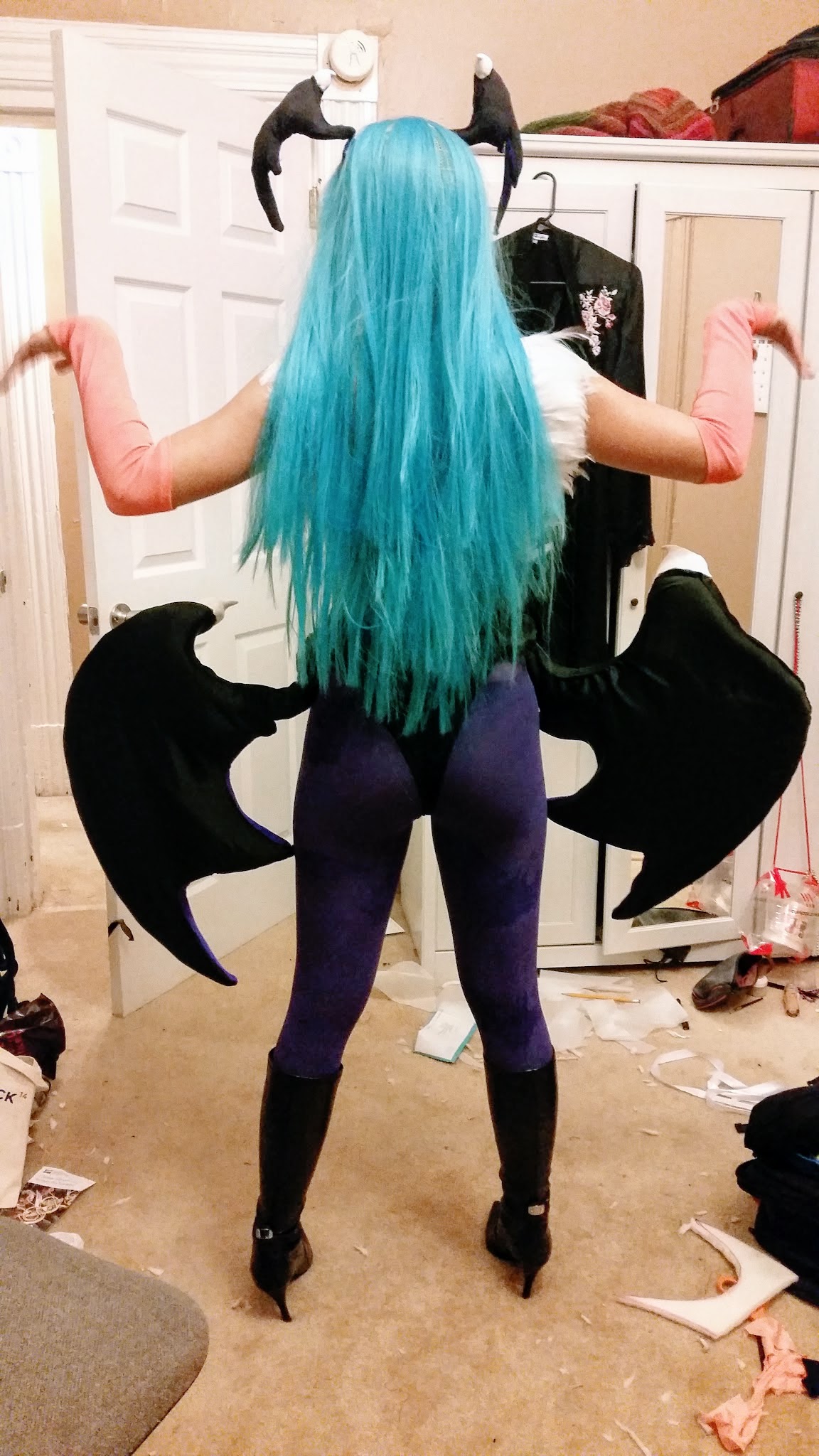 Photograph of a girl wearing a teal wig and a giant set of wings around her waist