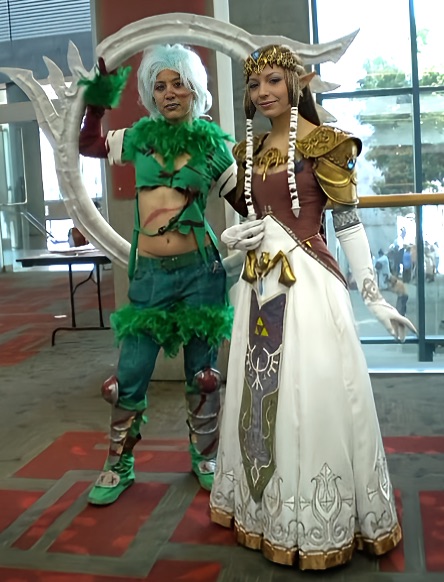 Photograph of a girl in green with a giant bladed ring standing next to a girl dressed as Princess Zelda