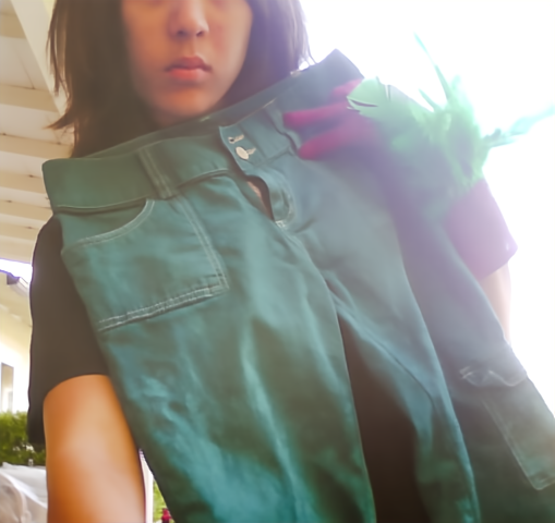 Photograph of a girl with brown hair wearing magenta gloves holding up green pants