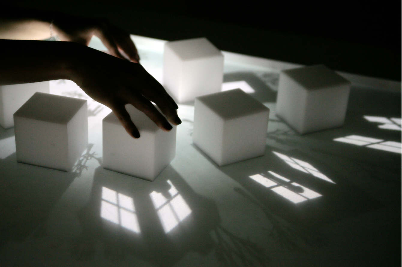 A photograph of people moving blocks on a table with projected windows